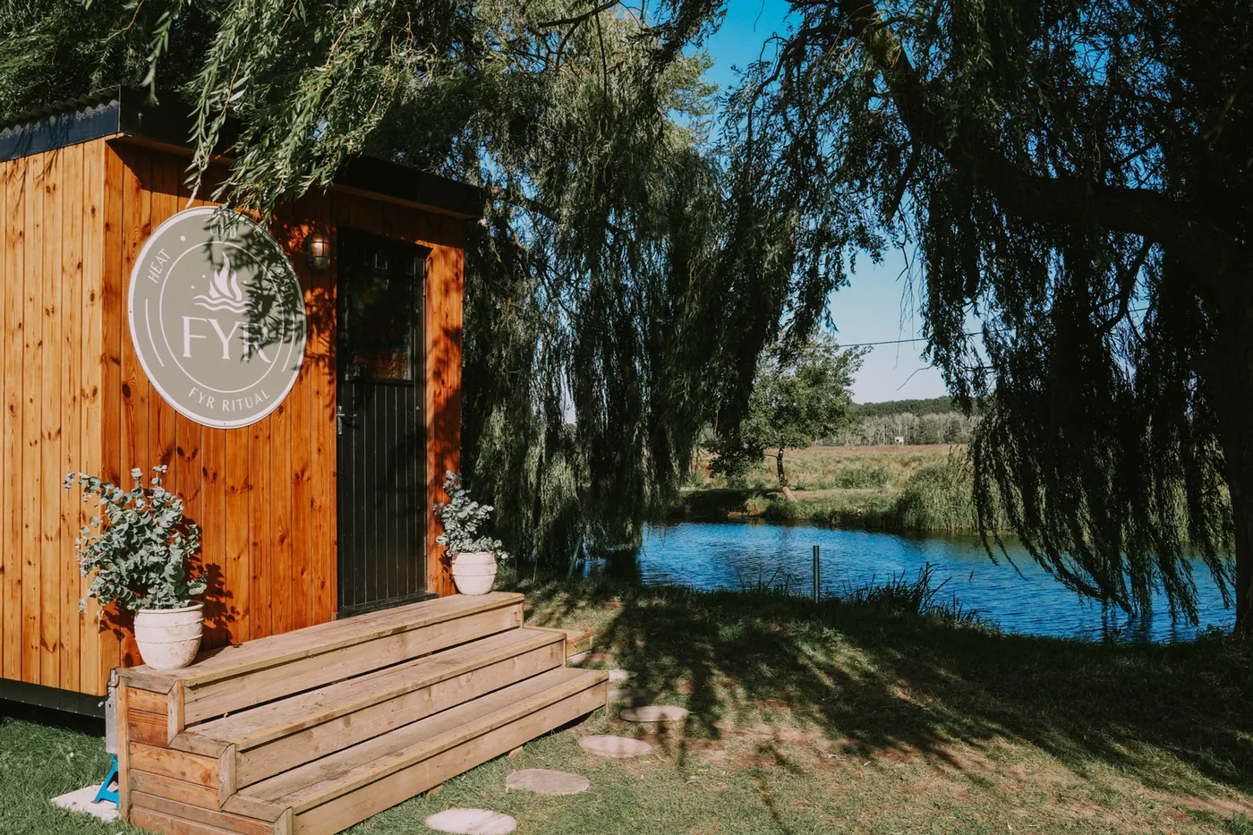The FYR Ritual cedar sauna under a willow beside the Dilham Canal