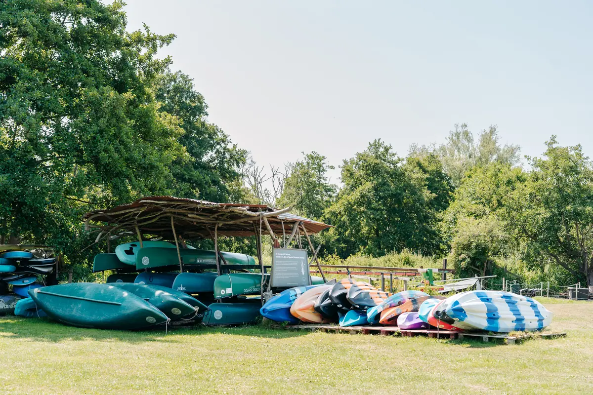 Canoes and kayaks lined up on the grass, ready for the water